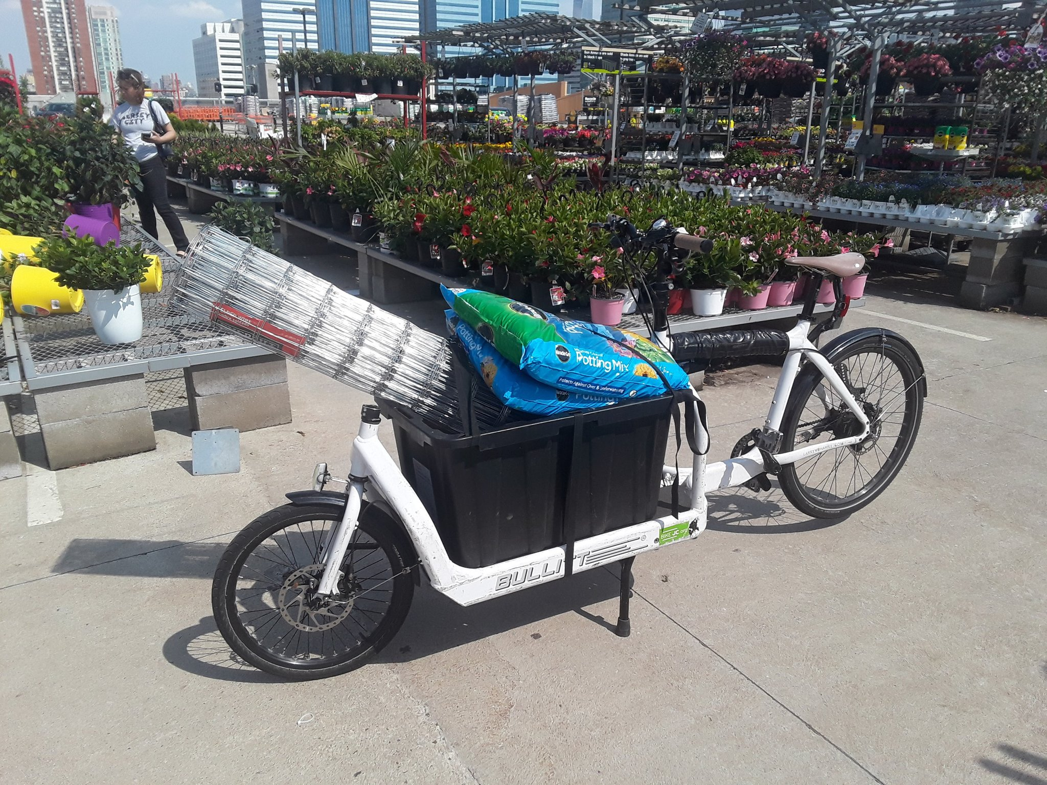 cargo bike loaded with potting soil and a roll of chain-link fence