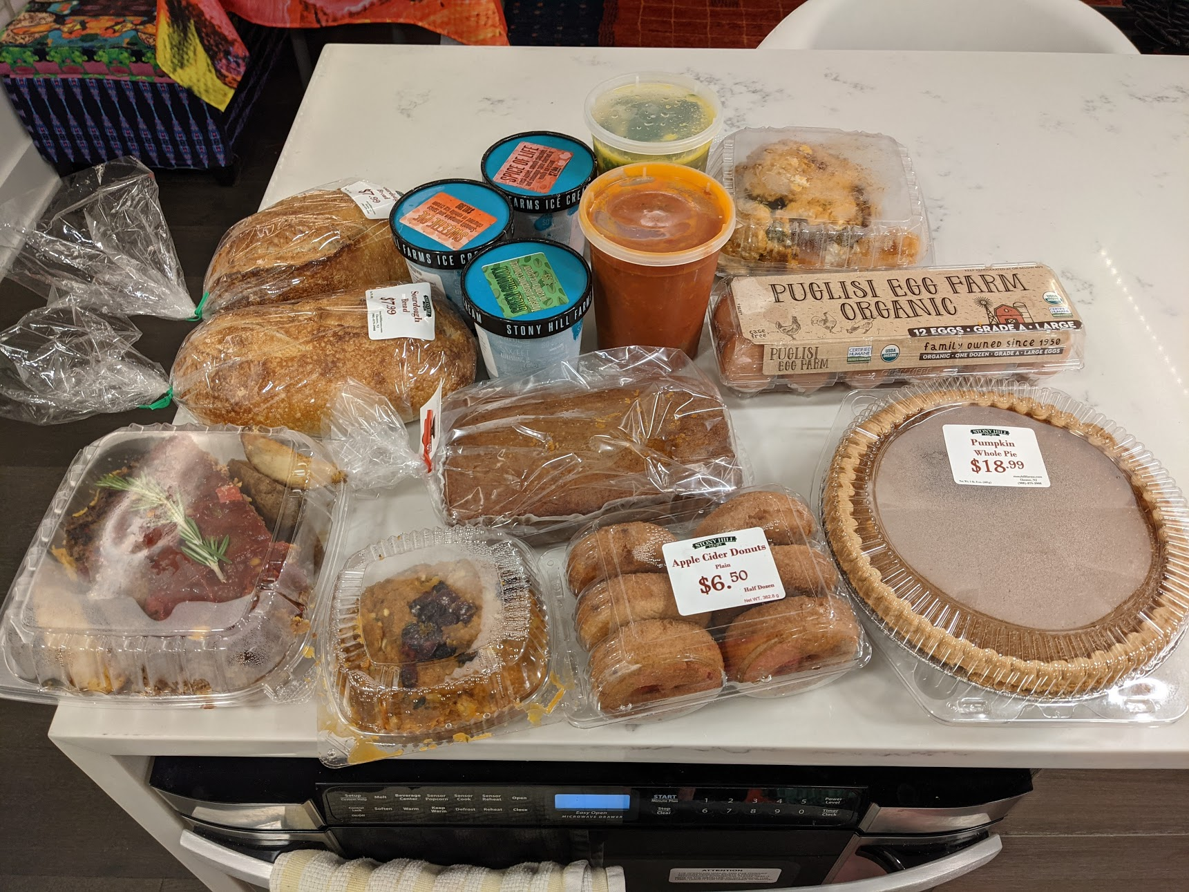 Groceries on counter-top: donuts, pumpkin pie, ice cream, bread