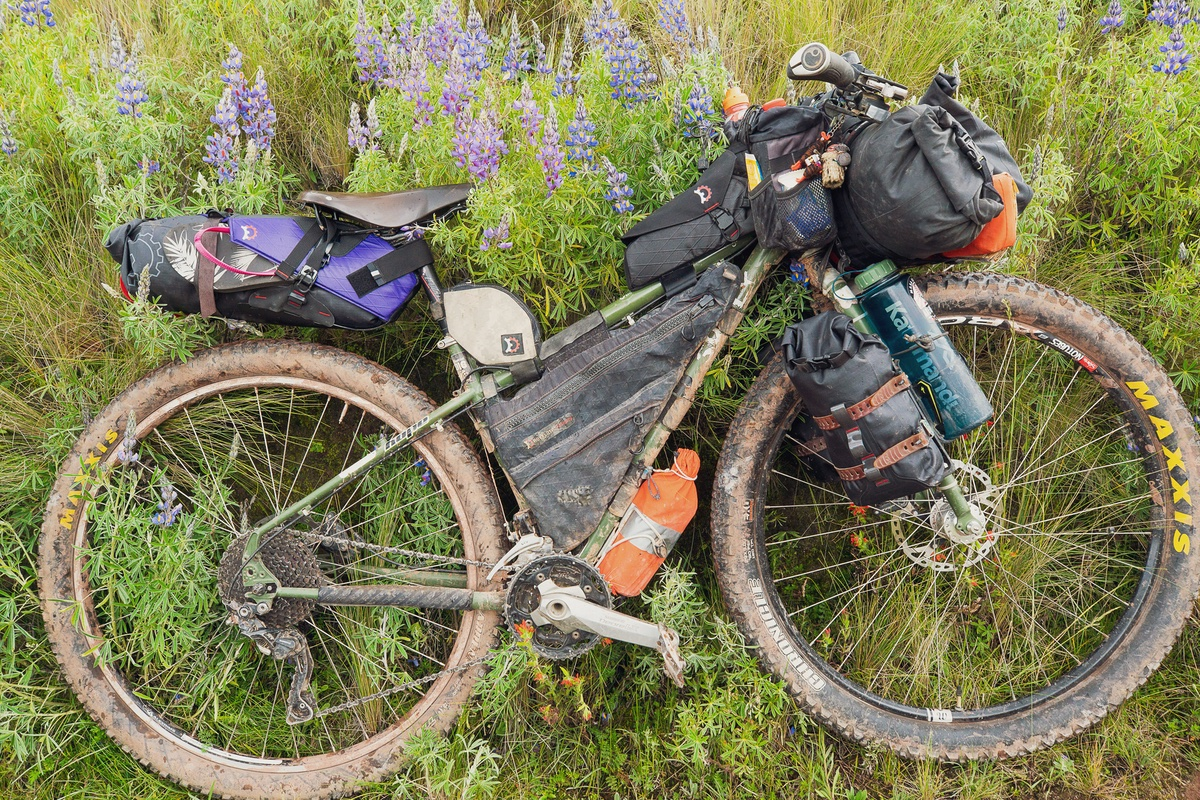 Revelate image of a dirty touring bike with may bags attached all over