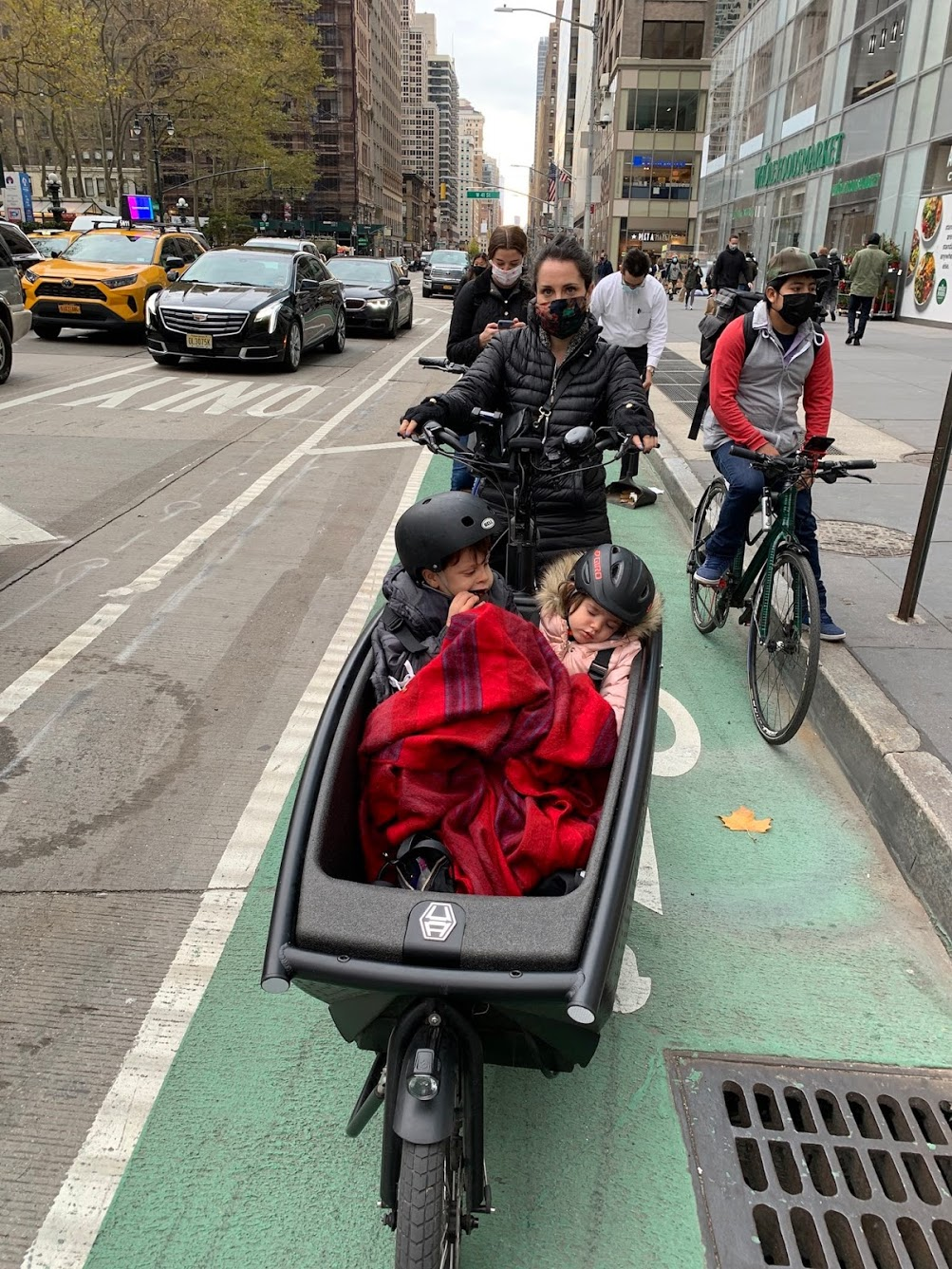 Woman cargo-biking in NYC with 2 children in a bakfiet