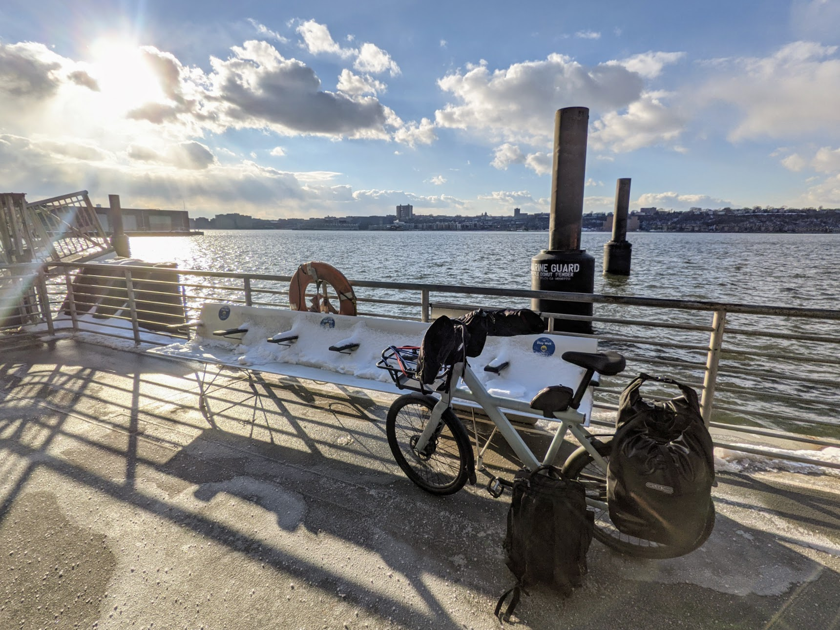 VanMoof at ferry dock with panniers, backpack, and fleece pogies on handlebars